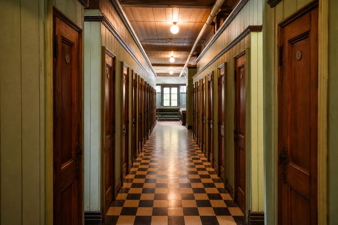 Row of wooden changing cabins with numbered doors inside a historic bath house corridor
