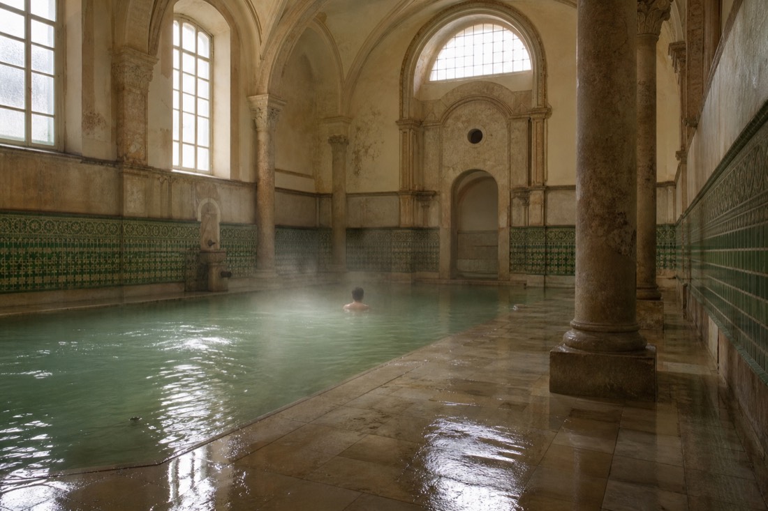 Indoor medicinal pool hall at a Budapest thermal bath with columns and still green water