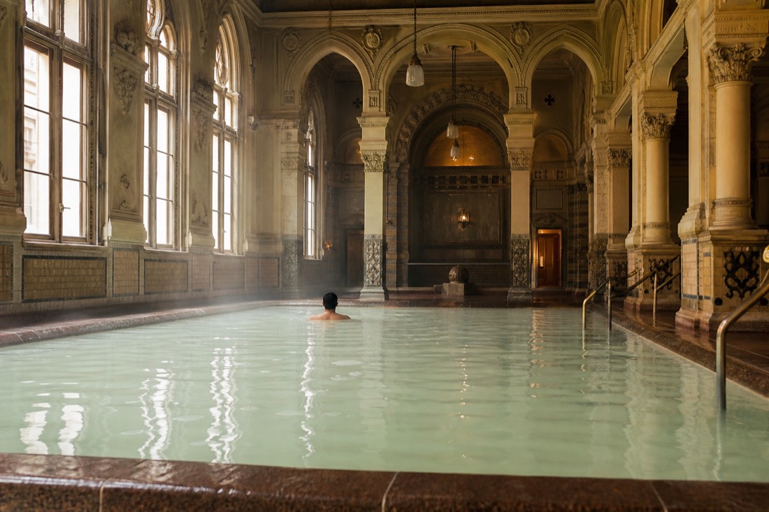 Pale green mineral-rich thermal water in an ornate indoor pool hall in Budapest