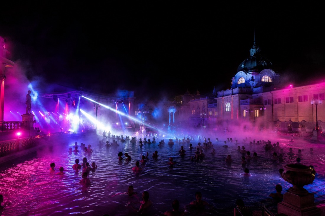 Night pool party atmosphere with lights and steam at an outdoor Budapest thermal pool