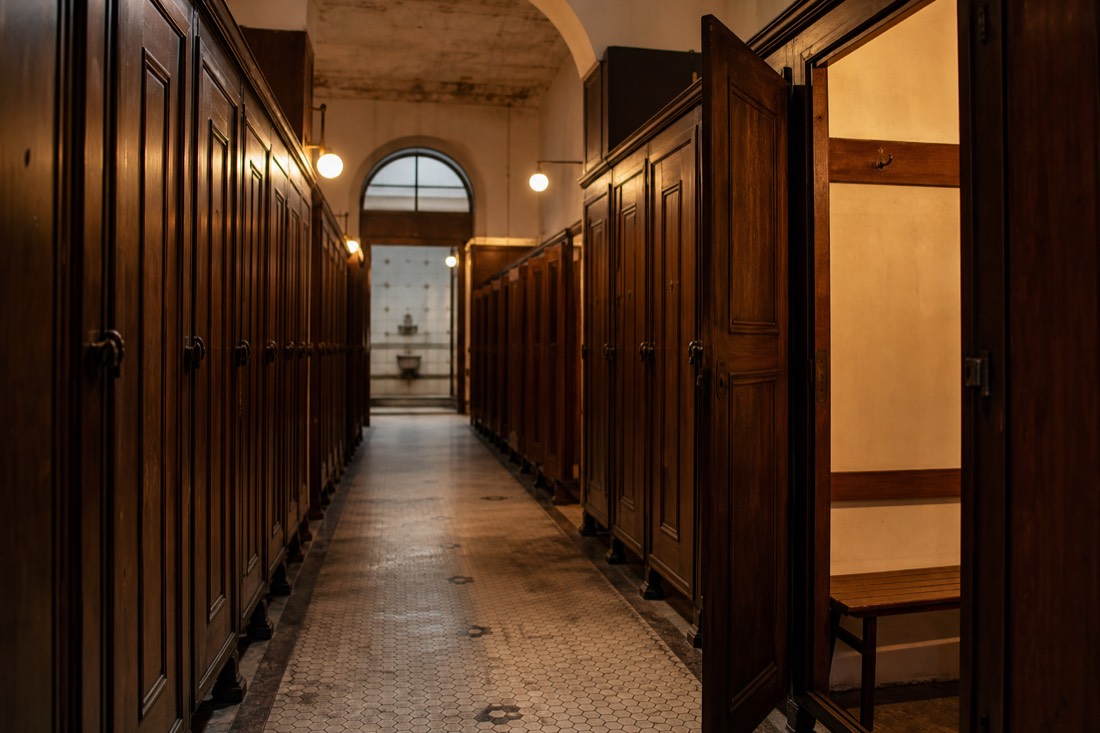 Corridor of wooden changing cabins inside a historic Budapest bathhouse with soft warm lighting