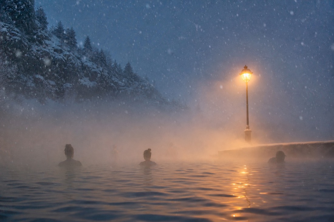 Thick steam drifting over bathers in an outdoor thermal pool during a Budapest snowfall