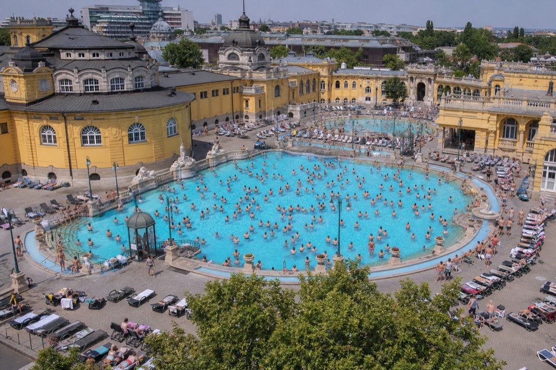 Busy weekend afternoon at a Budapest outdoor thermal pool with many bathers filling the water