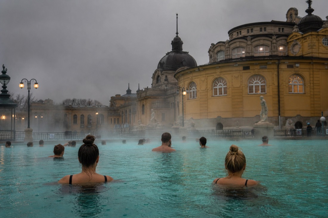 Rain falling on a steaming outdoor thermal pool while bathers stay warm in the water