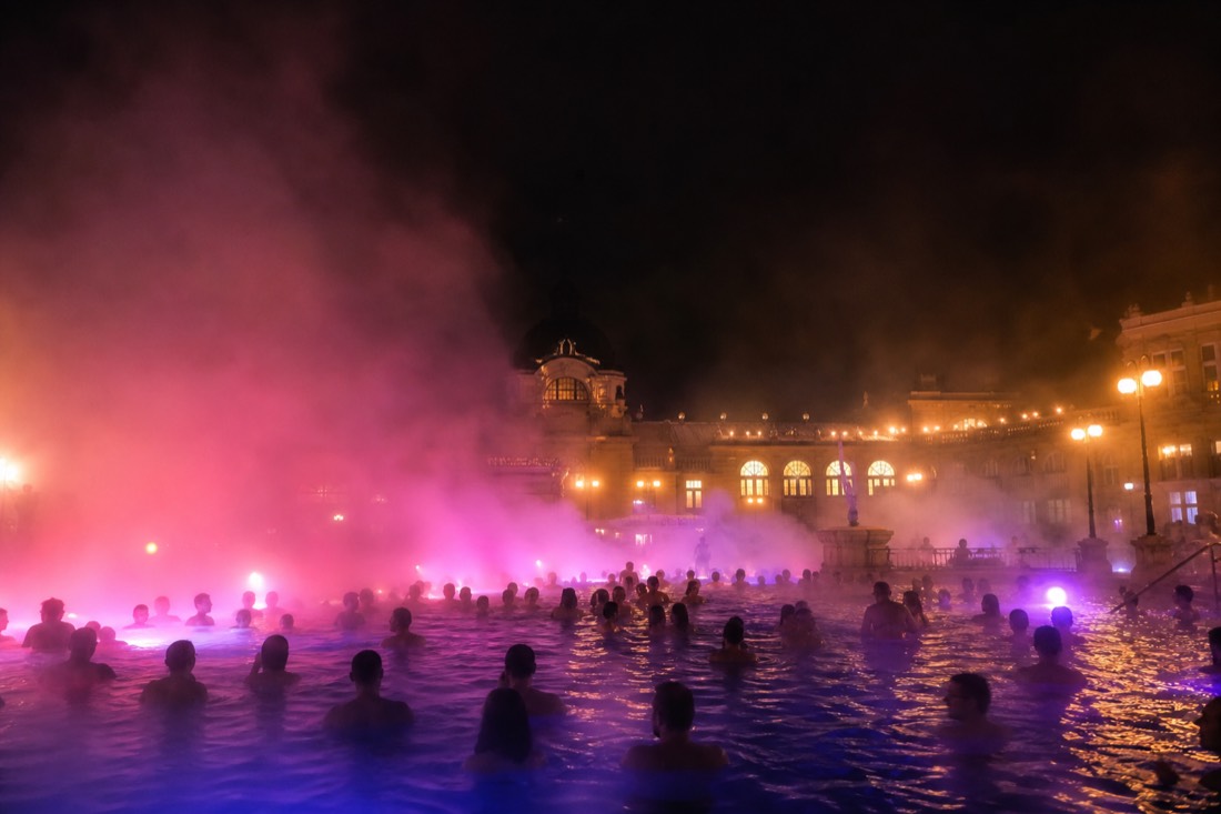 Steaming outdoor pool lit up at night in winter at a Budapest spa party