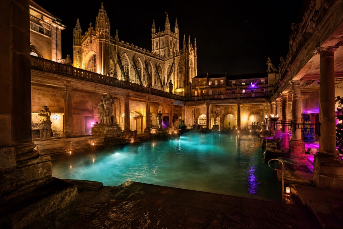 Budapest bath courtyard pool glowing at night with steam and festive lighting, no crowds visible