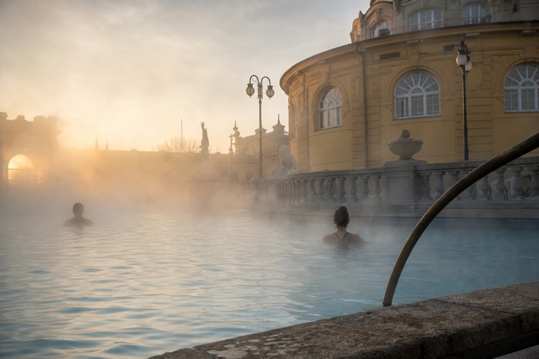 Steam rising off a hot outdoor thermal pool at a Budapest bath in cool morning air
