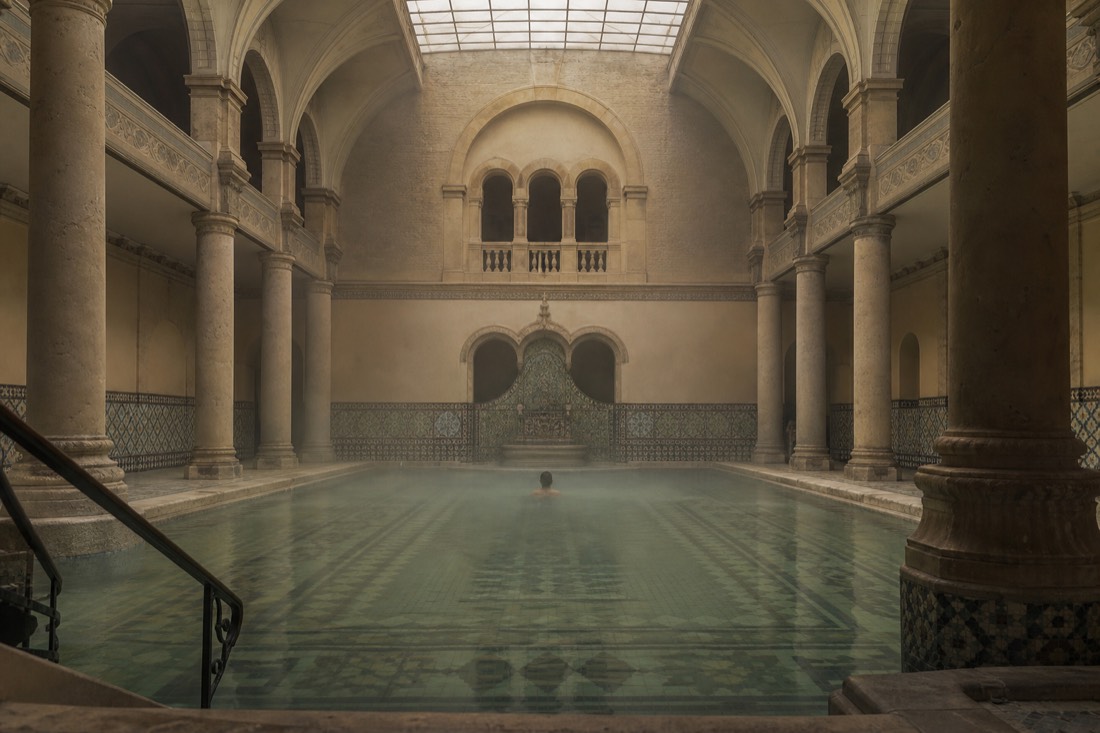 Indoor medicinal pool hall with warm mineral water and stone columns at a historic Budapest bath