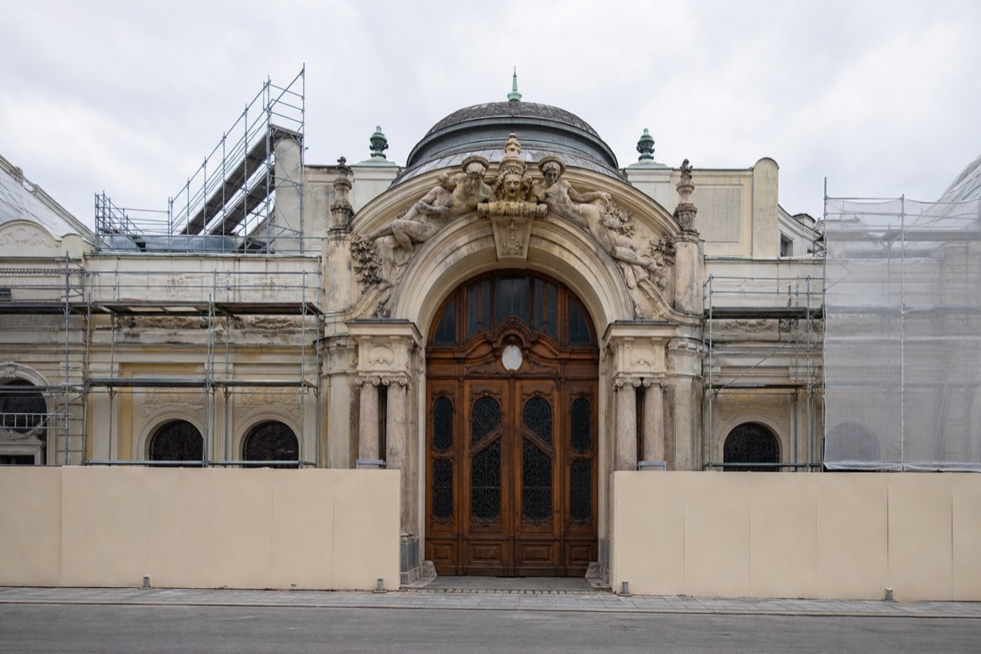 Closed ornate entrance doors of a historic Budapest bathhouse behind renovation hoarding