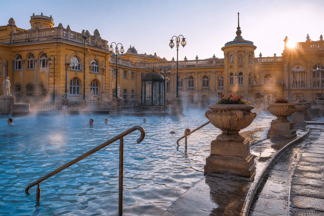 Morning light on the yellow facade and outdoor pools of an open Budapest thermal bath